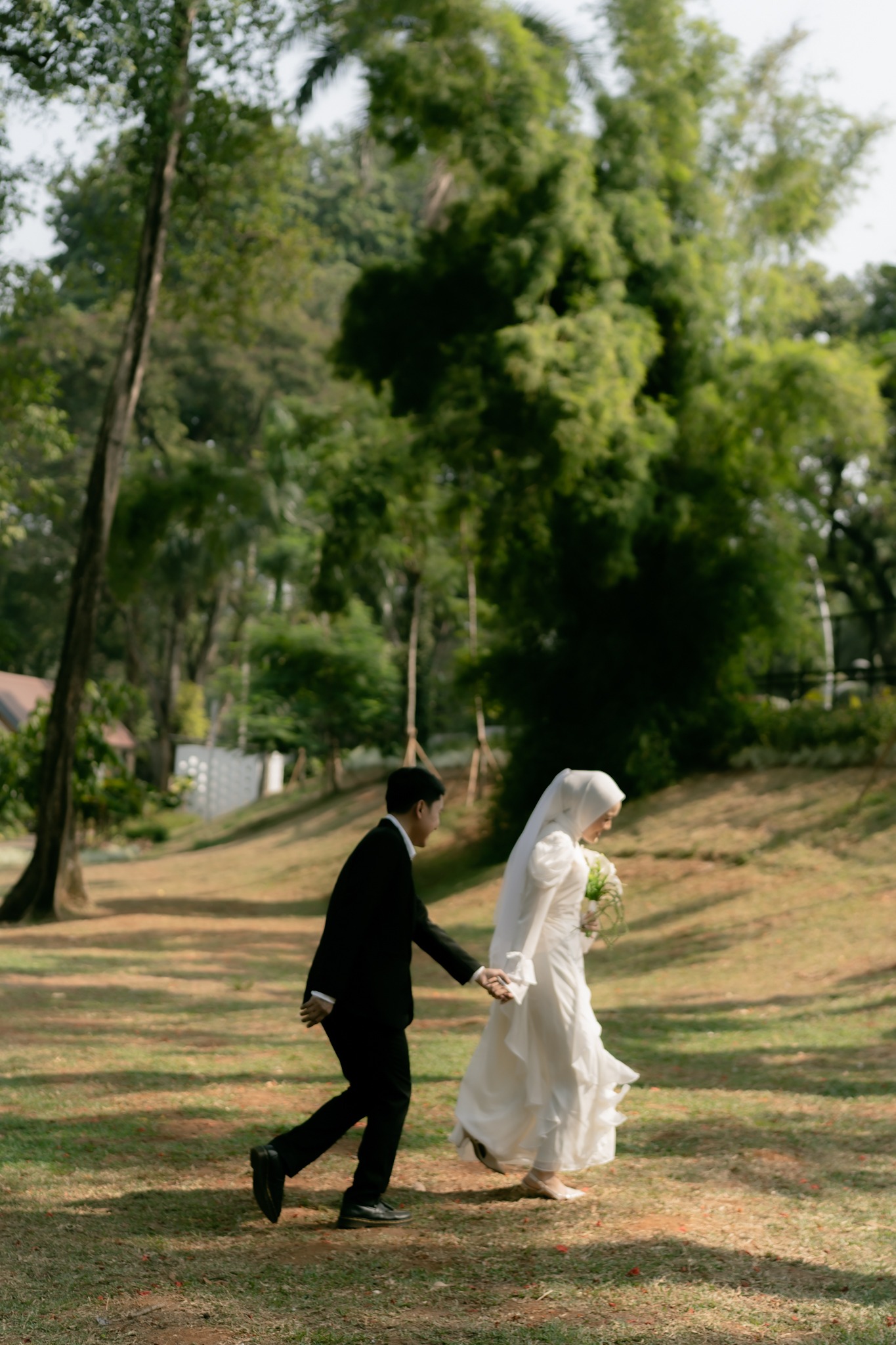 Monica dan Burhan berjalan bergandengan tangan di taman